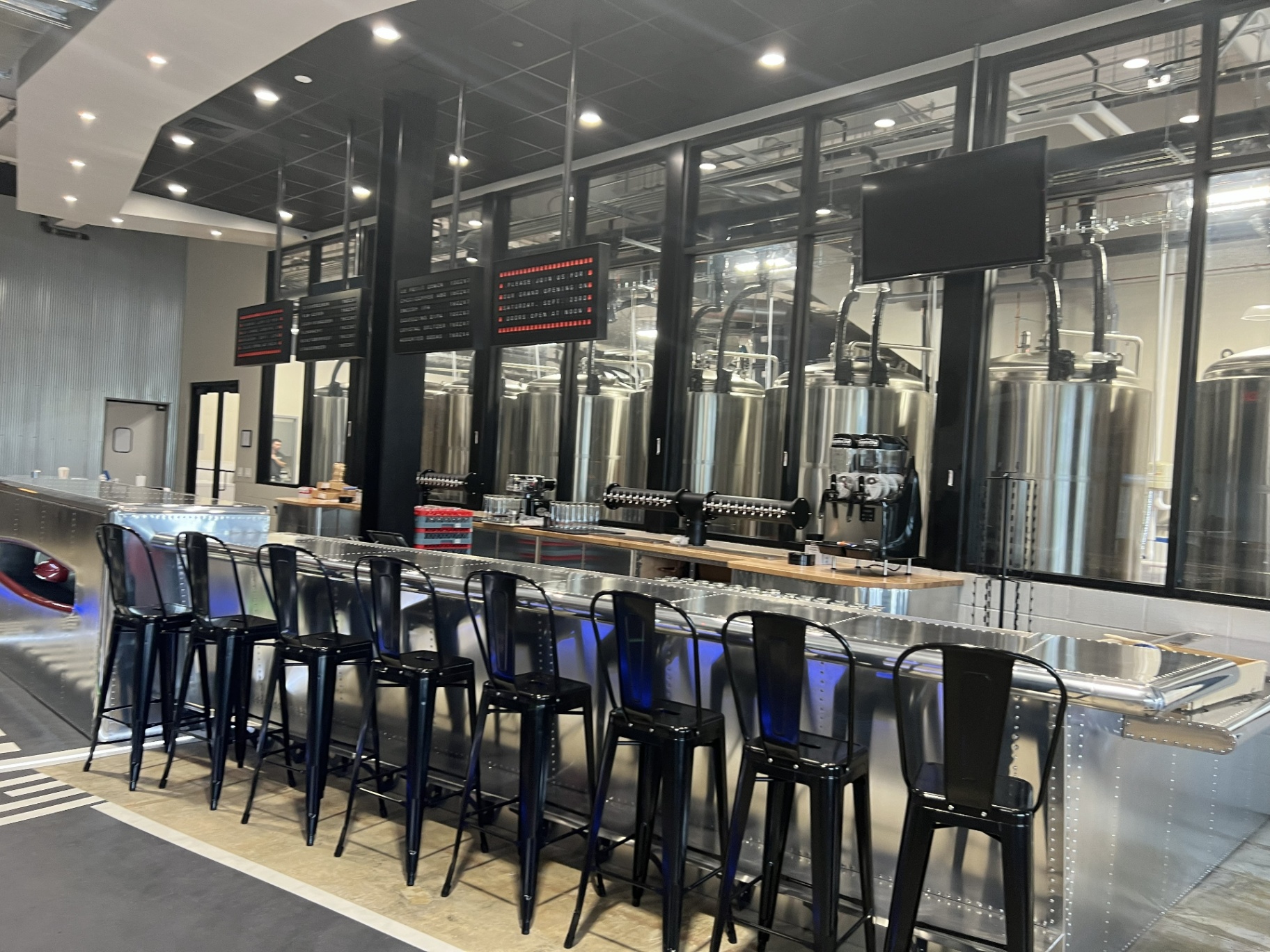 Bonesaw Brewing Deptford — custom riveted aluminium bar facing the glass-walled brewhouse