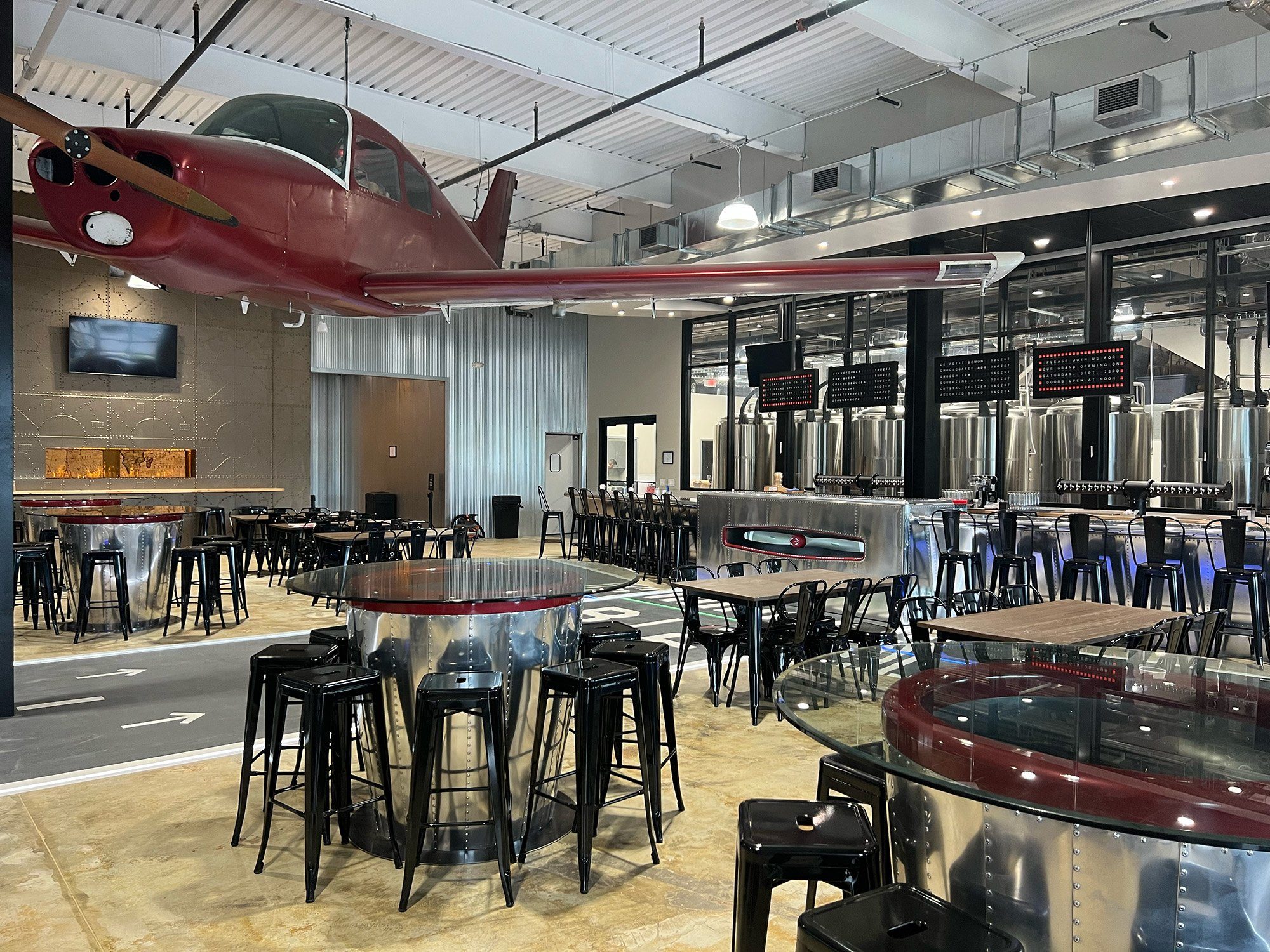 Bonesaw Brewing Deptford — suspended aircraft over the taproom and glass-walled brewhouse